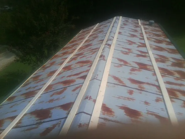 Rusted metal roof panels with new wood purlins before replacement — Storm Damage Roof Repair in Black Hawk by Roofing Brothers
