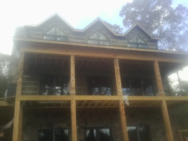 Dormers and porch framing on a large log home under construction — Roof Coating work by our crew in Black Hawk