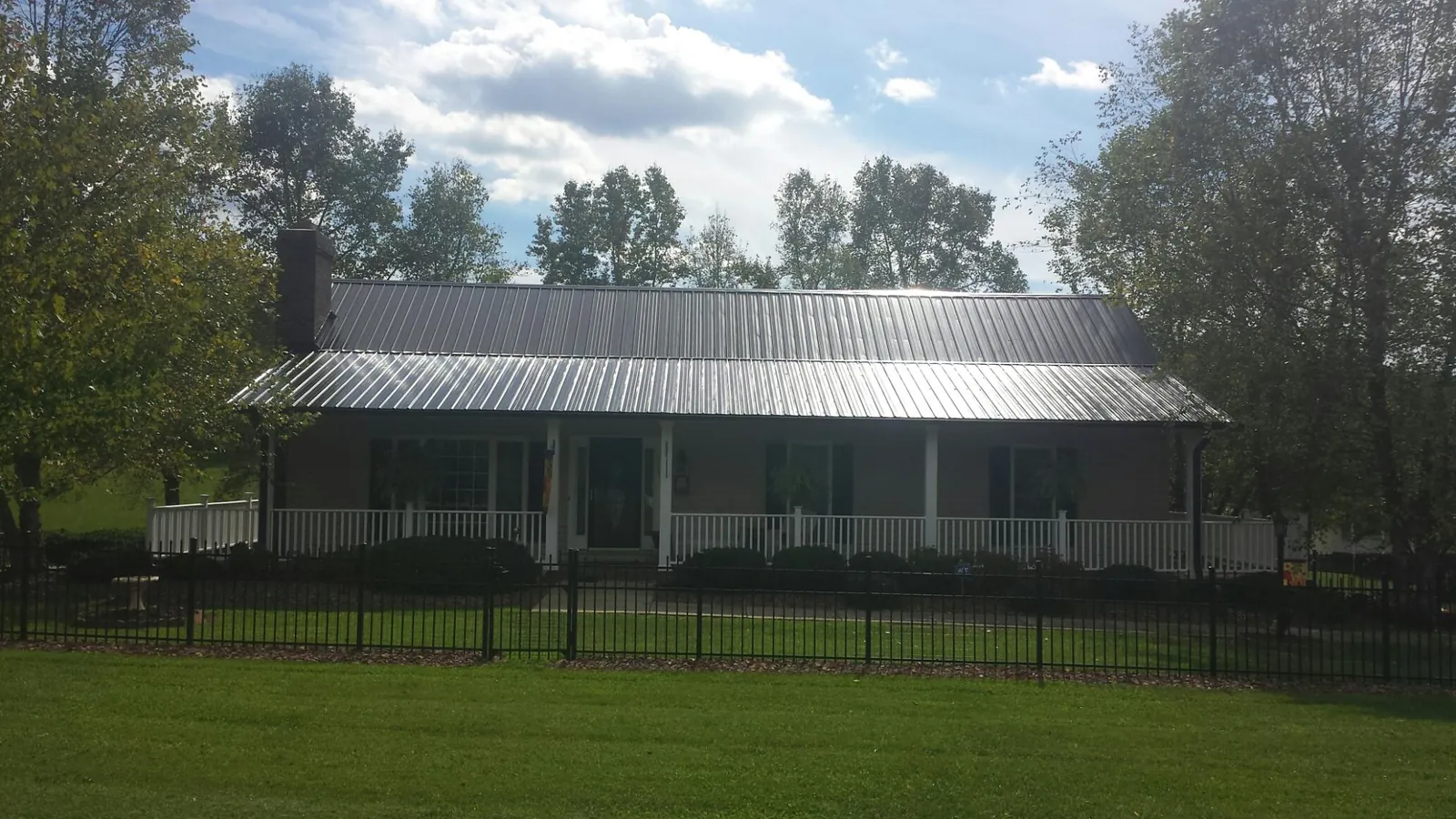 Gray metal roof on a brick ranch with a full width front porch — Gutter Guard Installation work by our crew in Black Hawk