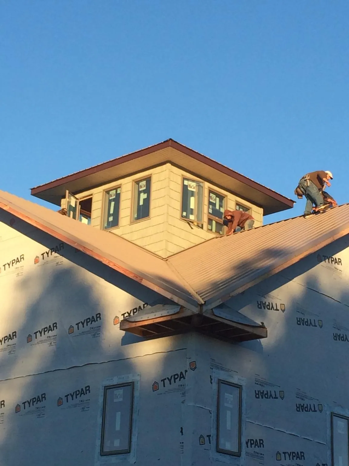 Roofers working around a rooftop cupola on a new metal roof at sunset — Roof Waterproofing in Black Hawk by Roofing Brothers